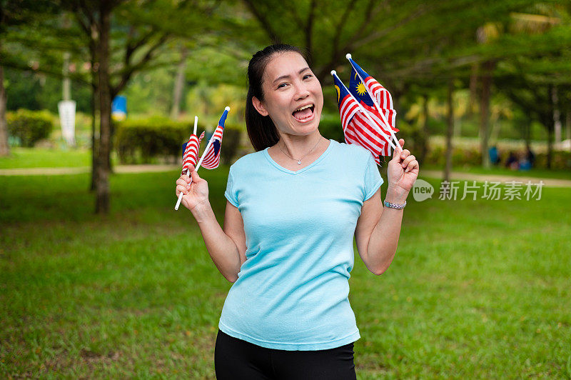 美丽的马来西亚妇女自豪地挥舞着马来西亚国旗。崇高的爱国主义精神和独立日，Hari Merdeka概念。